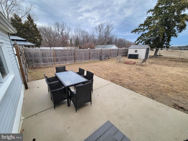 view of patio featuring a storage shed, a fenced backyard, outdoor dining area, and an outdoor structure