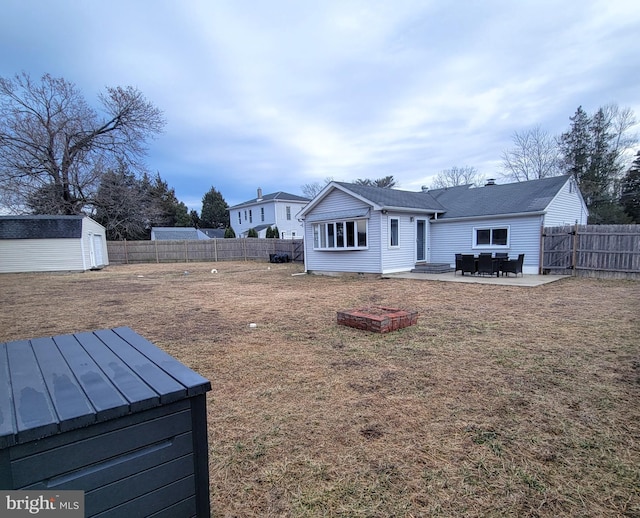 rear view of property with a storage shed, a fenced backyard, a lawn, and an outbuilding