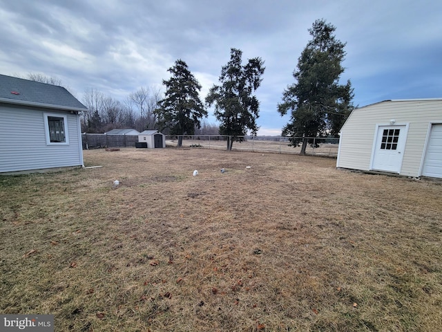 view of yard with a storage shed, fence, and an outbuilding