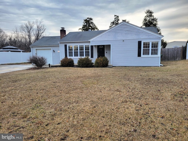 ranch-style house featuring a front yard, fence, a chimney, and an attached garage