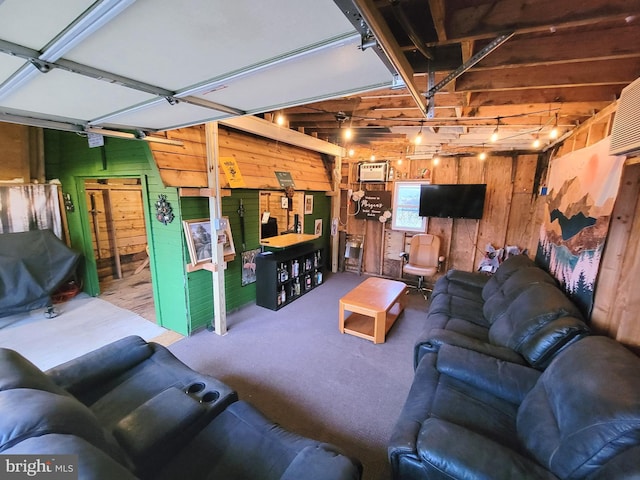 carpeted living room featuring a garage and wood walls