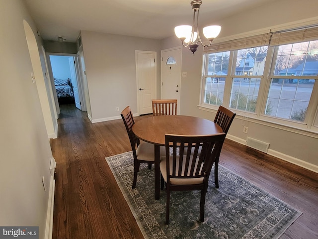 dining area with a chandelier, visible vents, baseboards, and wood finished floors