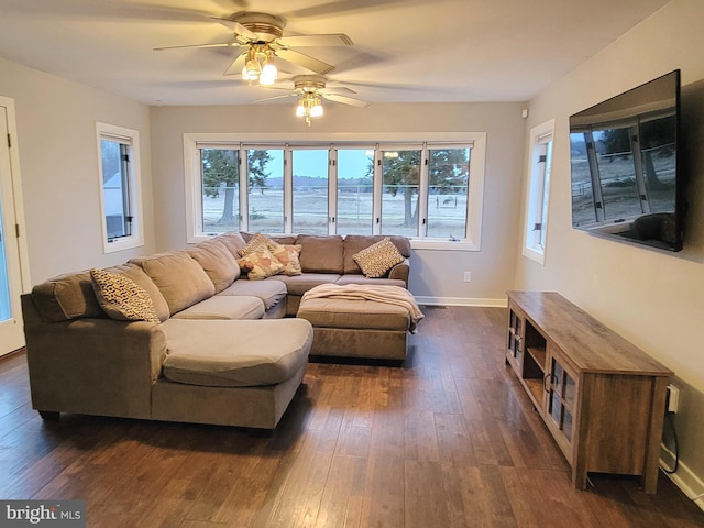 living area with plenty of natural light, baseboards, and dark wood finished floors