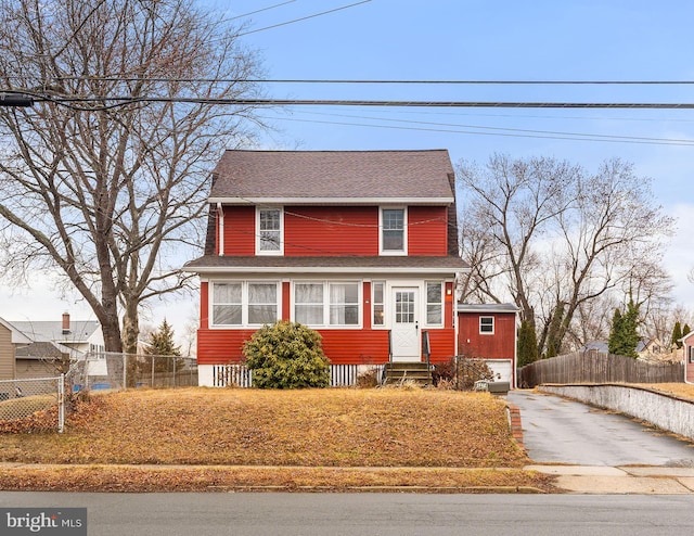 view of front of house with entry steps, fence, and roof with shingles