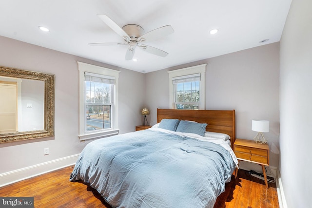 bedroom with multiple windows, ceiling fan, baseboards, and wood finished floors