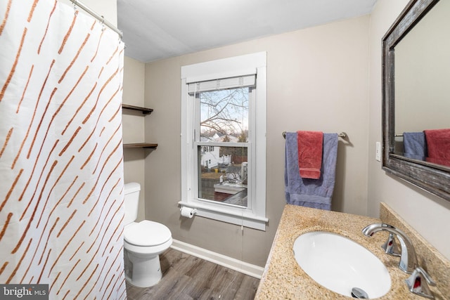 bathroom featuring vanity, wood finished floors, toilet, and baseboards