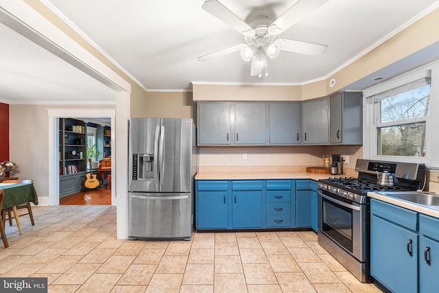 kitchen featuring stainless steel appliances, crown molding, light countertops, blue cabinetry, and a sink