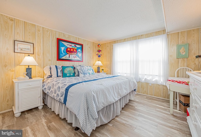 bedroom featuring a textured ceiling, wood walls, and light wood-type flooring