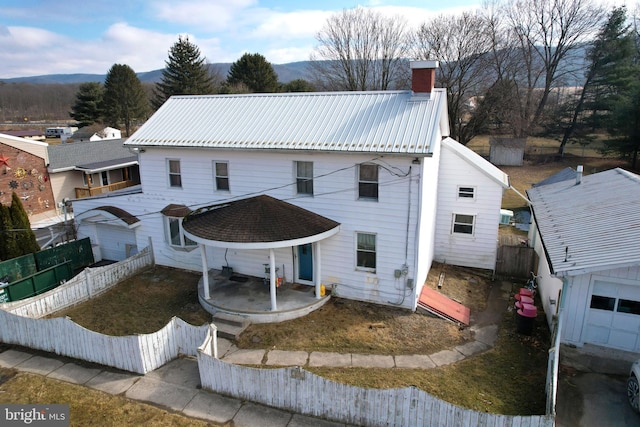 view of front of home with metal roof, a mountain view, fence, a chimney, and a patio area