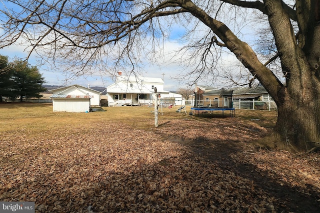 view of yard with a trampoline and fence