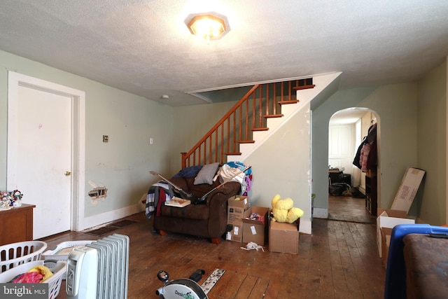 living room with arched walkways, a textured ceiling, hardwood / wood-style flooring, and baseboards