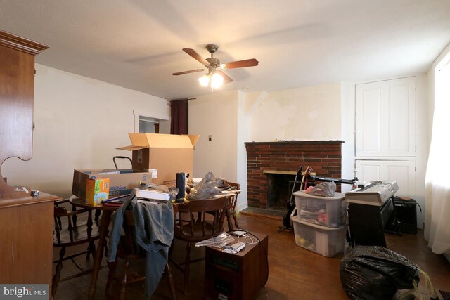 dining room with wood finished floors, a fireplace, and ceiling fan