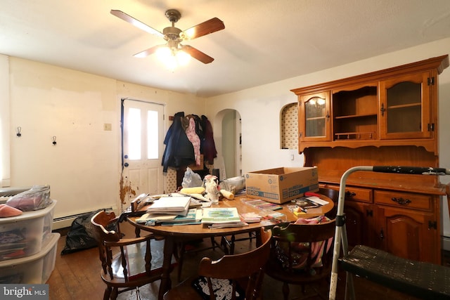 dining area featuring ceiling fan, a baseboard heating unit, arched walkways, and wood finished floors