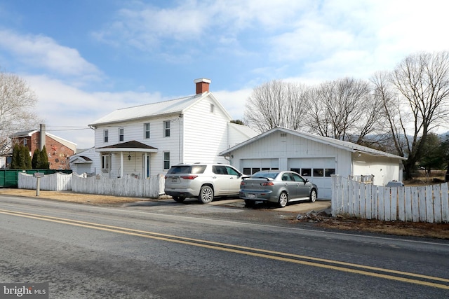 view of front of house featuring metal roof, fence, and a detached garage