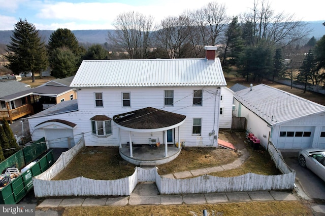 view of front facade with metal roof, a patio, fence private yard, a mountain view, and a chimney