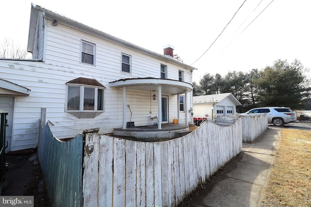 view of front facade featuring fence and a chimney