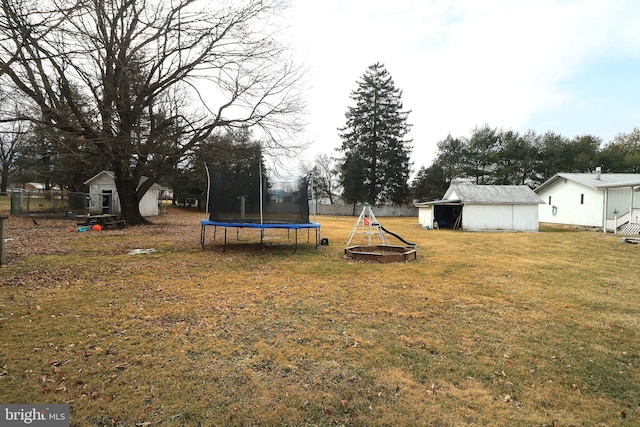 view of yard with a trampoline, a storage unit, a playground, and an outbuilding