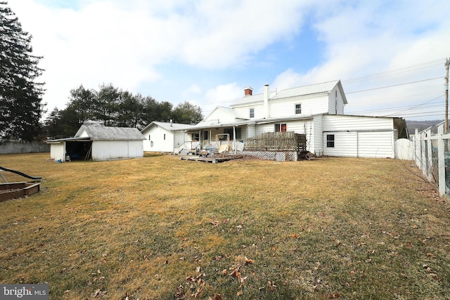 back of house featuring an outbuilding, fence, and a lawn