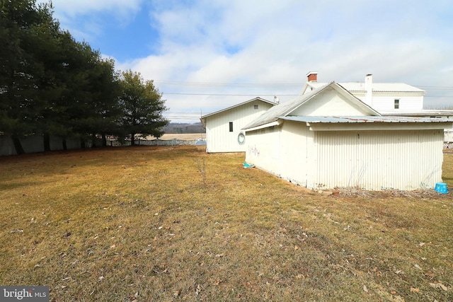 view of side of property featuring metal roof and a lawn