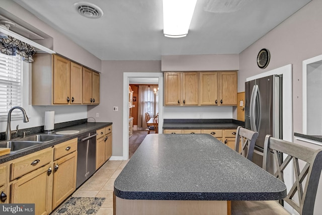 kitchen featuring stainless steel appliances, dark countertops, visible vents, and a sink