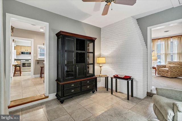 interior space with ceiling fan, baseboards, and light tile patterned flooring