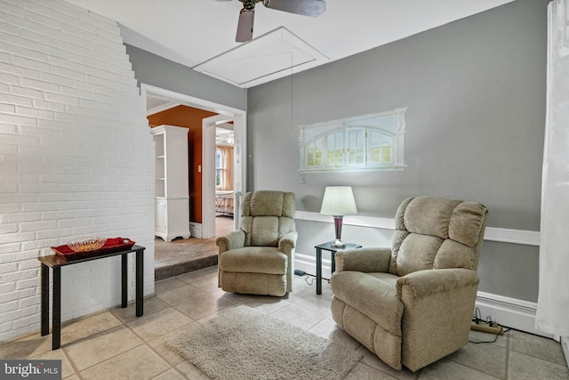 sitting room with brick wall, tile patterned flooring, and attic access