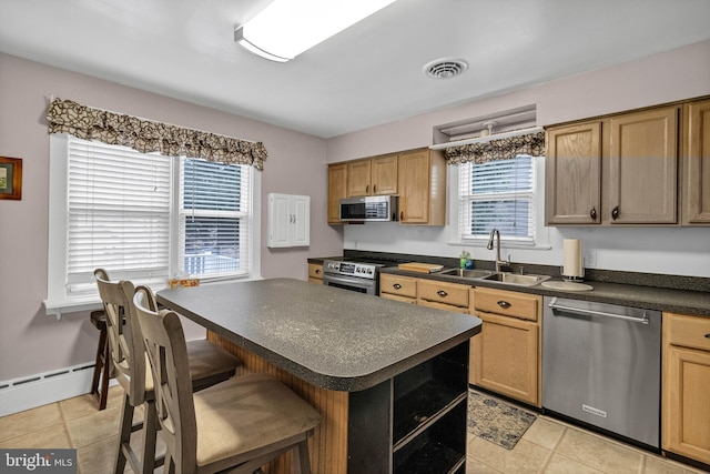 kitchen featuring visible vents, dark countertops, appliances with stainless steel finishes, a breakfast bar, and a sink