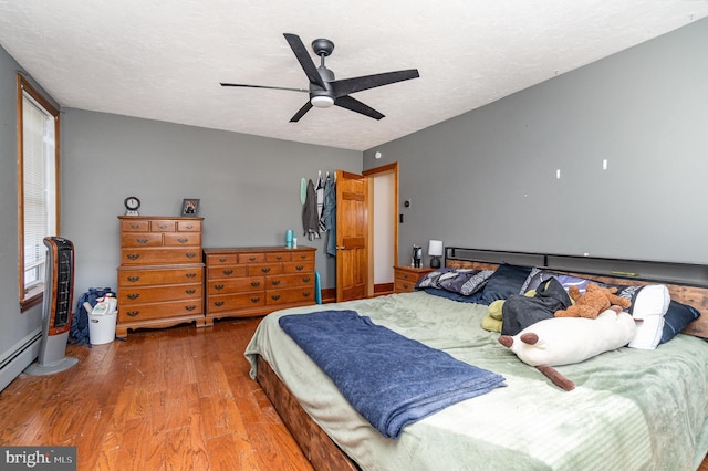 bedroom with a textured ceiling, wood finished floors, and a ceiling fan