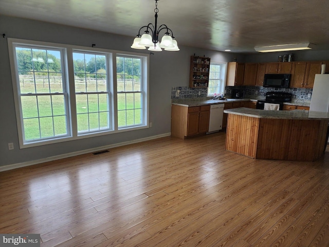 kitchen with visible vents, decorative backsplash, brown cabinets, light wood-type flooring, and black appliances