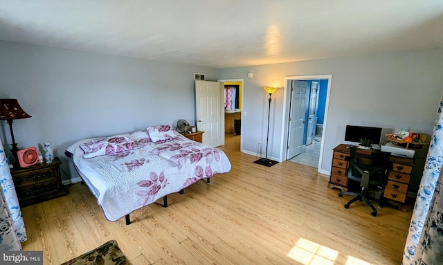 bedroom with visible vents, baseboards, and wood finished floors