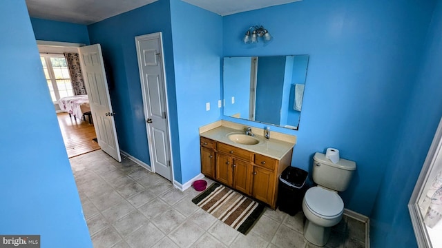 bathroom featuring toilet, baseboards, ensuite bathroom, and vanity