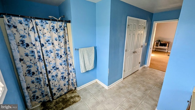 bathroom featuring a shower with curtain, tile patterned flooring, and baseboards