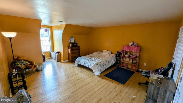 bedroom with lofted ceiling, wood-type flooring, and baseboards