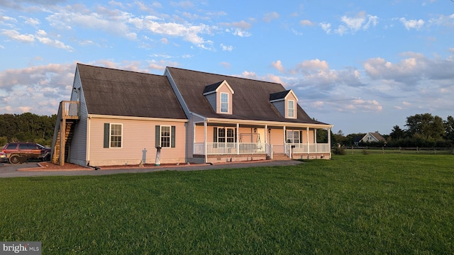 view of front of house featuring covered porch, stairway, and a lawn