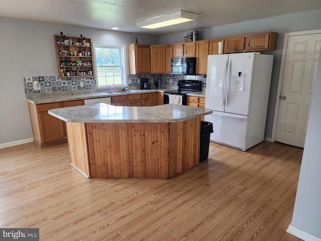 kitchen featuring backsplash, light countertops, light wood-style flooring, and black appliances