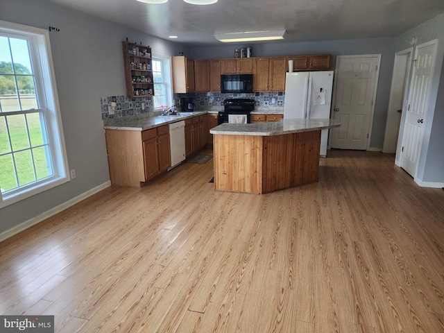 kitchen with plenty of natural light, backsplash, black appliances, and light wood finished floors