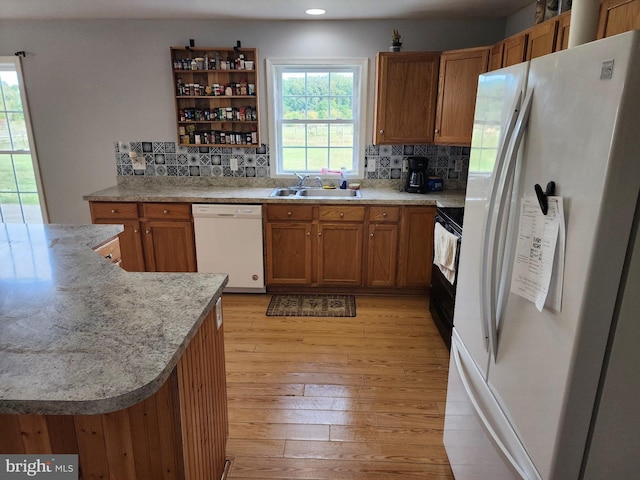 kitchen with brown cabinetry, white appliances, a sink, and light wood-style flooring