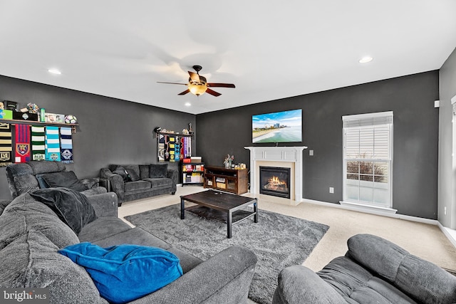 living room featuring ceiling fan, a fireplace, baseboards, and carpet flooring