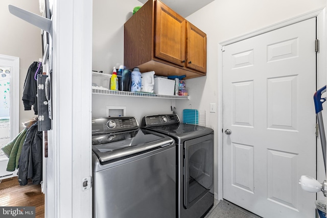 clothes washing area featuring cabinet space and washer and clothes dryer