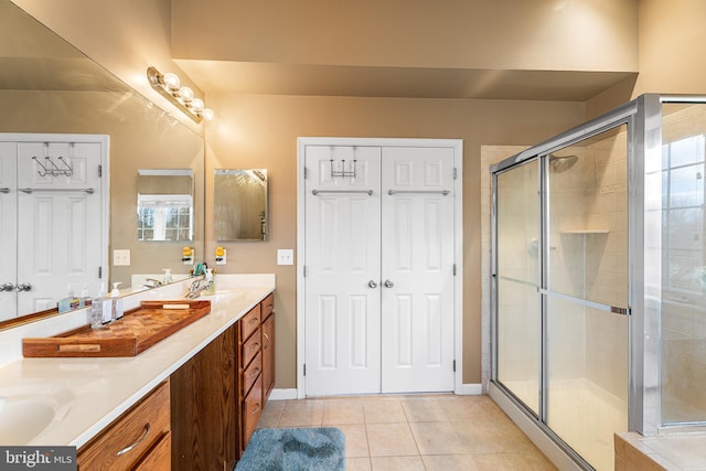 bathroom featuring double vanity, a stall shower, tile patterned flooring, and a sink