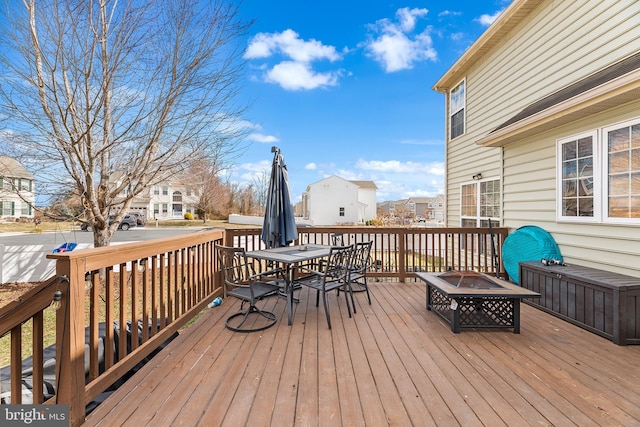 wooden terrace featuring a residential view, a fire pit, and outdoor dining space