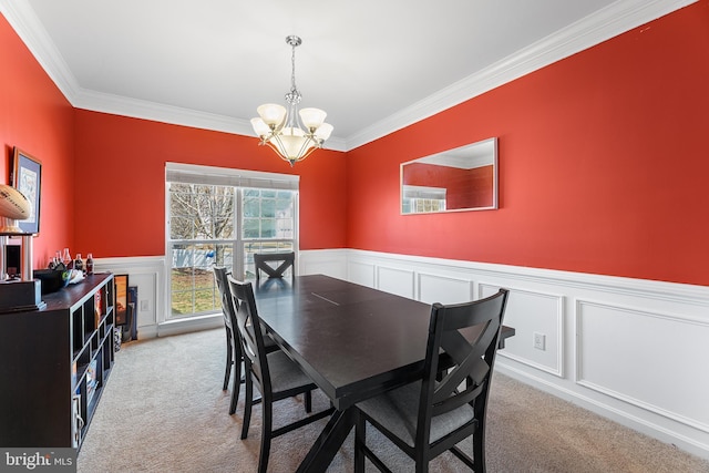 dining room with a chandelier, a wainscoted wall, carpet, and crown molding