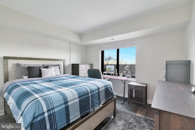 bedroom with wood finished floors, visible vents, and baseboards