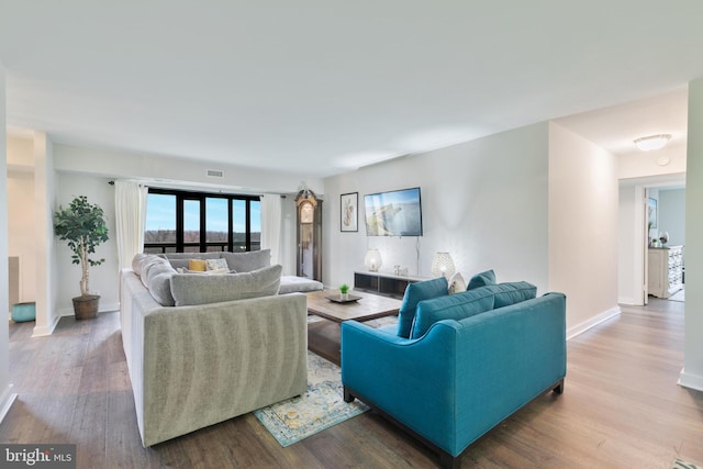 living room featuring visible vents, baseboards, and wood finished floors