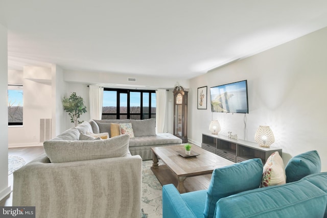 living room featuring visible vents, baseboards, and wood finished floors