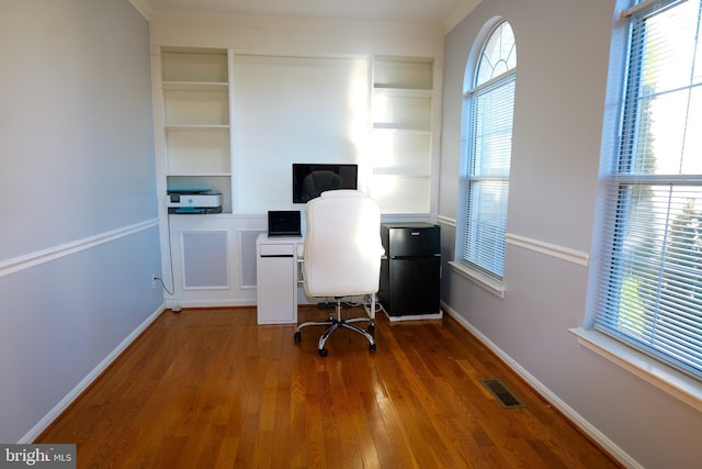 unfurnished office featuring ornamental molding, visible vents, baseboards, and wood finished floors