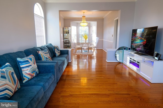 living area with ornamental molding, wood finished floors, and baseboards