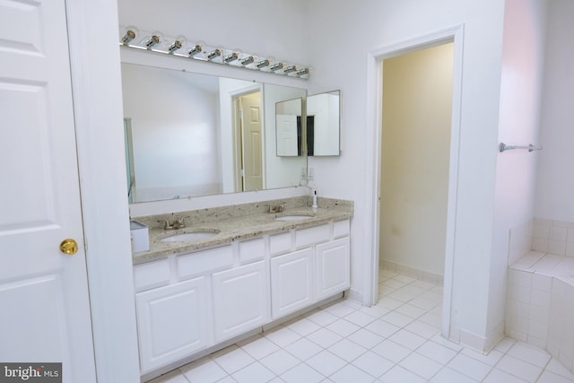 bathroom with double vanity, tile patterned flooring, a bathtub, and a sink