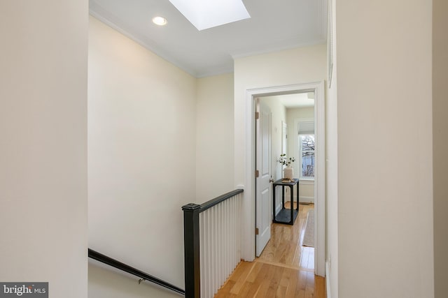 hallway with light wood-style floors, a skylight, crown molding, and recessed lighting