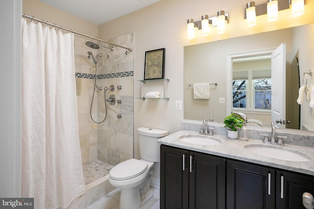 full bathroom featuring toilet, double vanity, a sink, and tiled shower